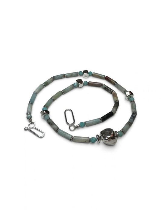 A beaded necklace with cylindrical beads in shades of gray, sage green, and black, accented with small turquoise-blue beads and silver-toned metal spacers, clasp, and a large polished silver bead at the end, displayed on a clean white background.
