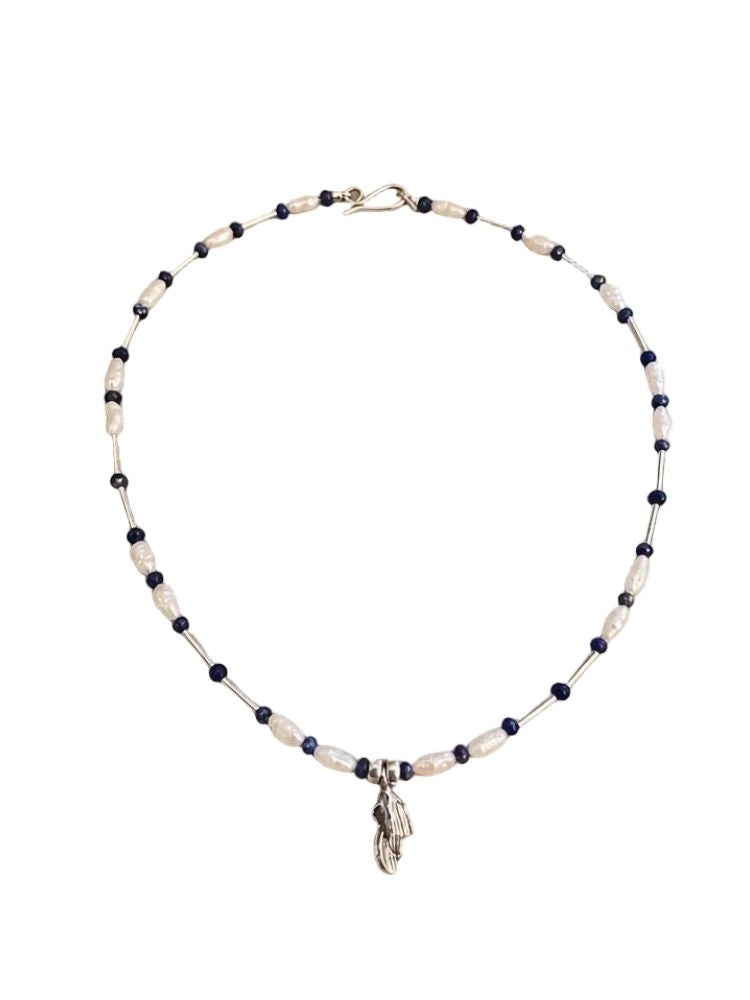 A beaded necklace featuring alternating dark navy blue beads and textured off-white beads, with a small silver-toned feather charm hanging from the center, displayed on a clean white background.