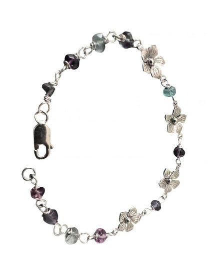 A silver-toned beaded bracelet featuring heart-shaped and flower-shaped charms, accented with faceted beads in purple, gray, and light blue, displayed on a clean white background.