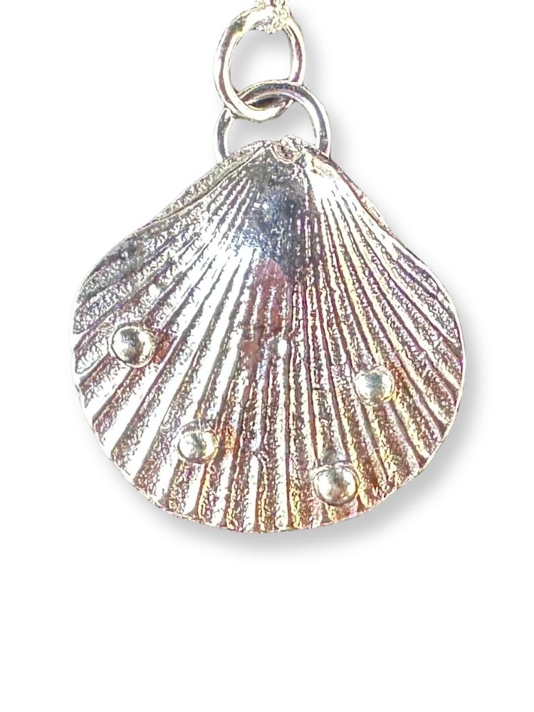A silver-toned shell-shaped pendant charm with a textured, ribbed surface and three small metallic bead accents, shown on a plain white background.